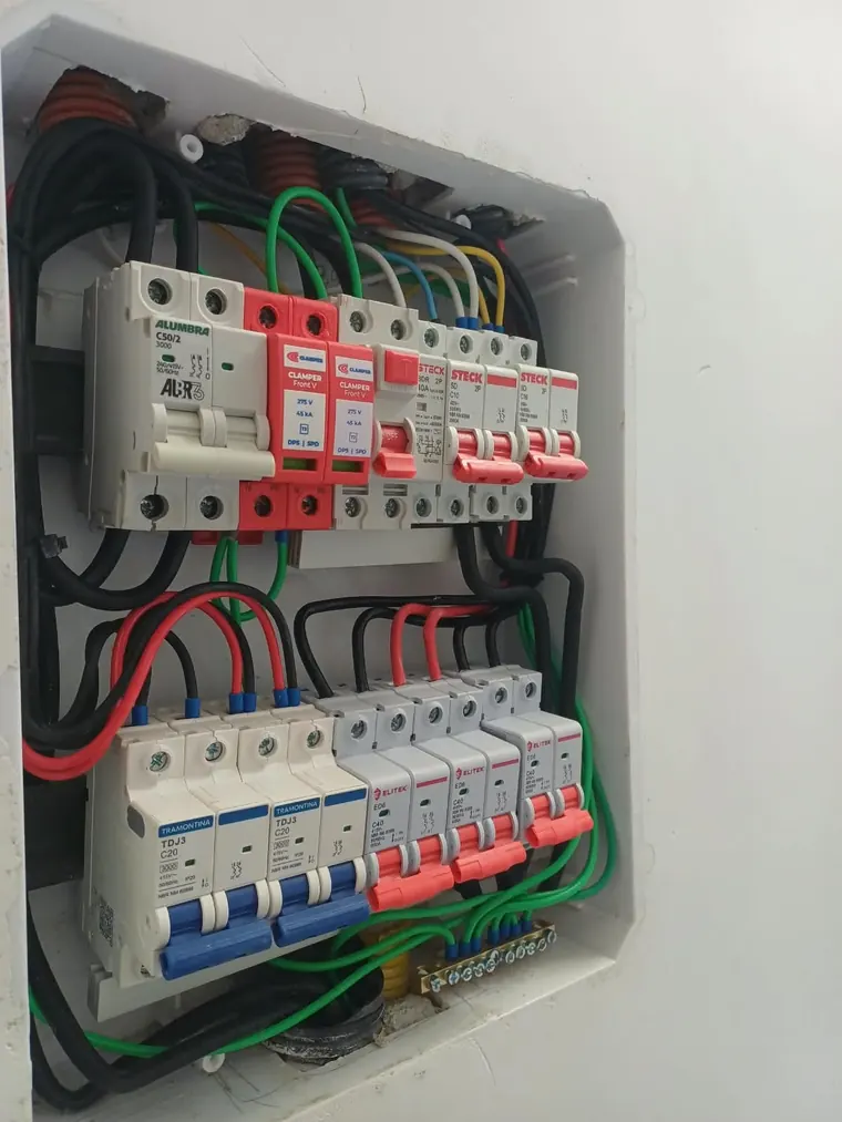 Quadro aberto com DPS contra surtos, DR e disjuntores, com a fiação organizada.